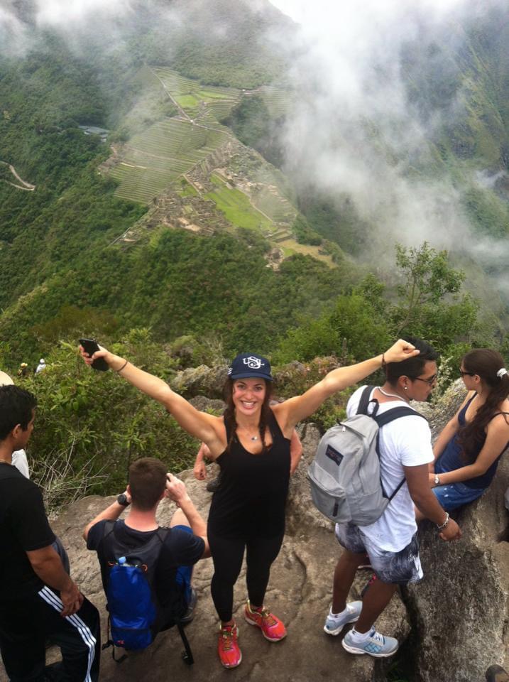 Woman celebrating at Machu Picchu viewpoint.