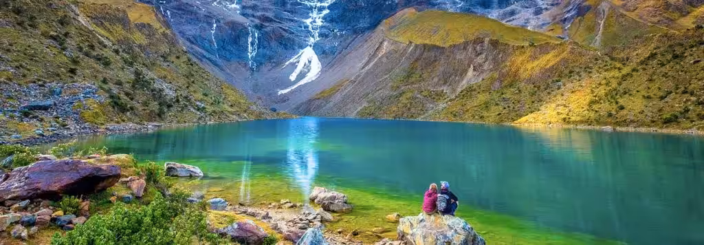 Deux visiteurs contemplant le lac Humantay et le glacier